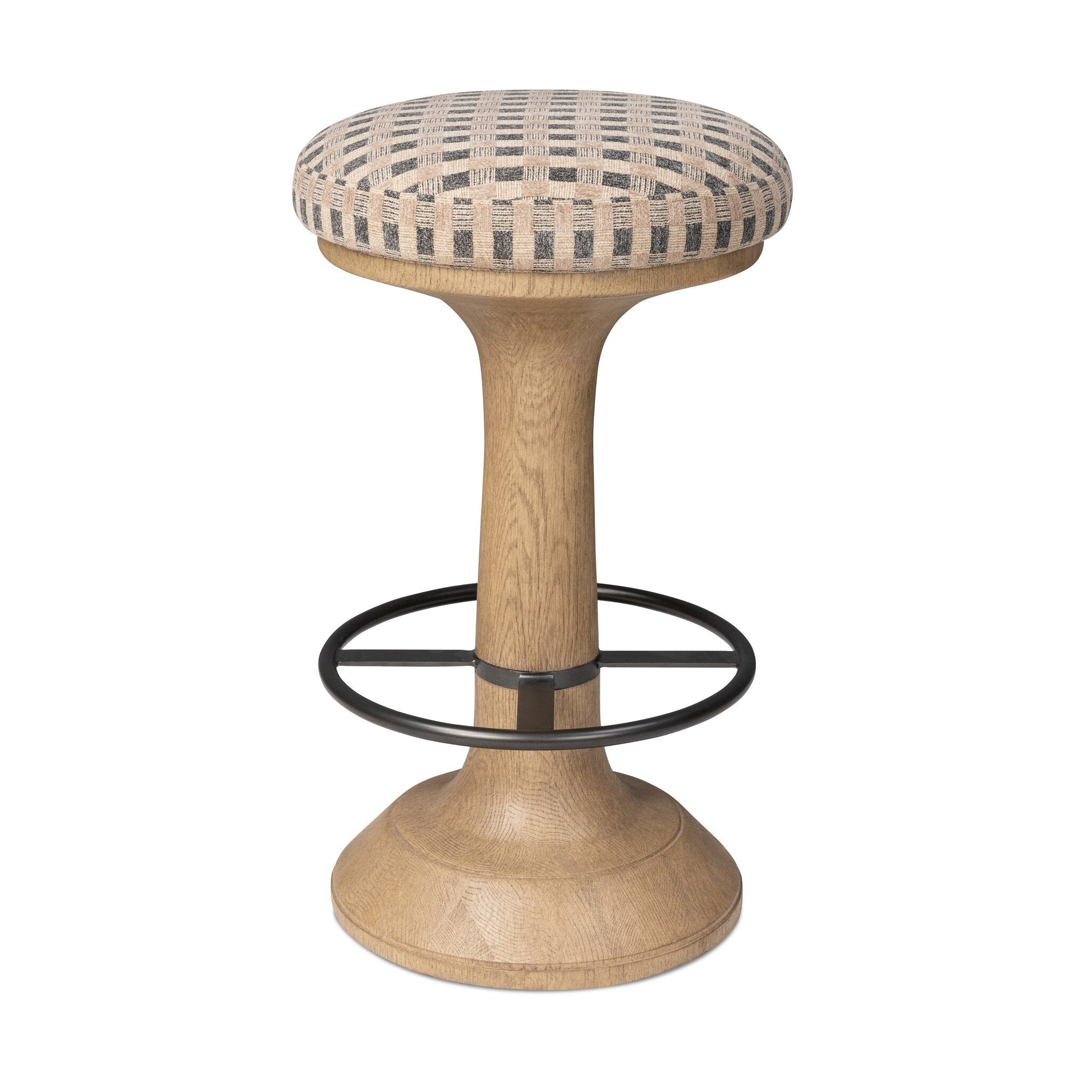 A modern bar stool with a light oak wood pedestal base, a black metal footrest ring, and a round cushioned seat upholstered in a beige and gray woven pattern, isolated on a white background.